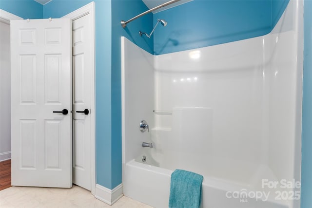 bathroom featuring shower / tub combination and baseboards