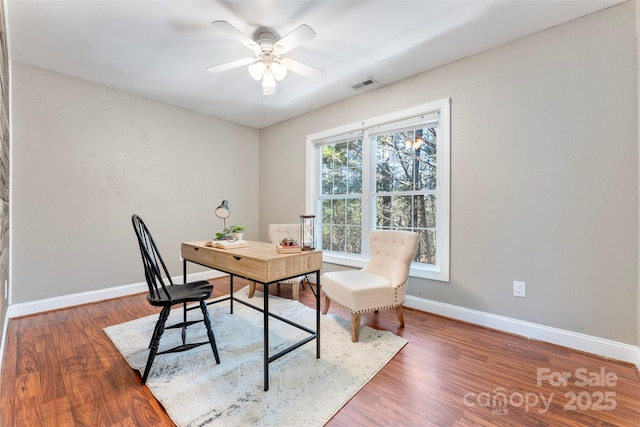 office featuring a ceiling fan, baseboards, visible vents, and dark wood-style flooring