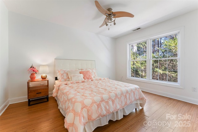 bedroom with a ceiling fan, visible vents, light wood-style flooring, and baseboards