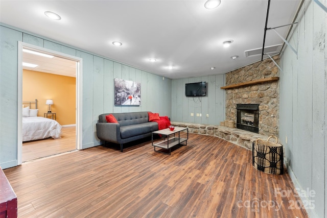 living area featuring baseboards, a fireplace, visible vents, and wood finished floors