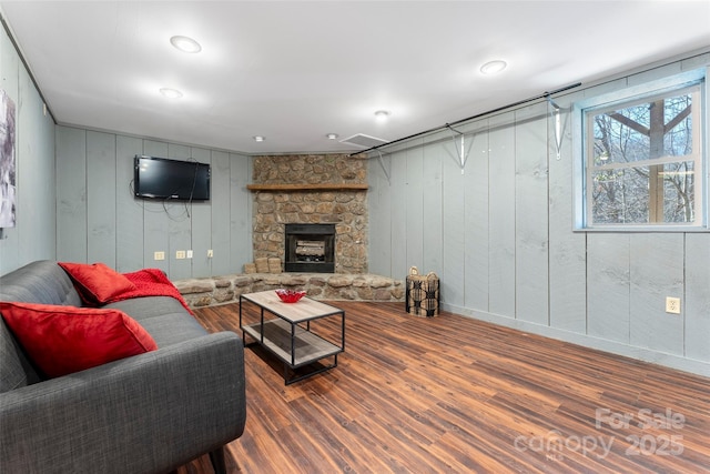 living area with wood finished floors and a stone fireplace