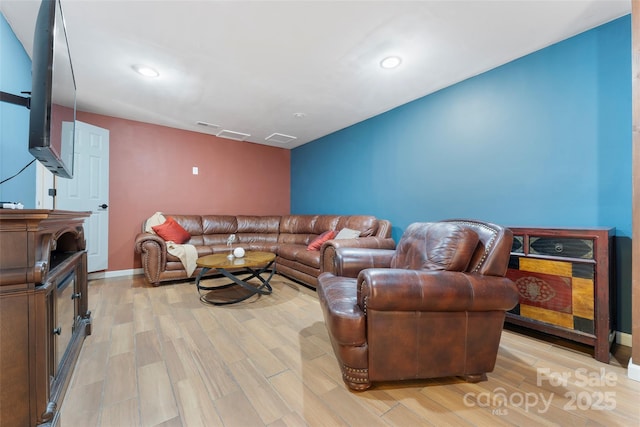 living room featuring baseboards, light wood-type flooring, visible vents, and recessed lighting