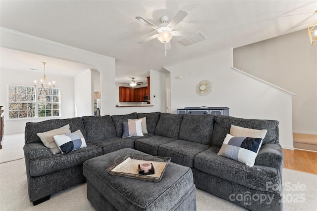 living area featuring ceiling fan with notable chandelier, baseboards, and ornamental molding