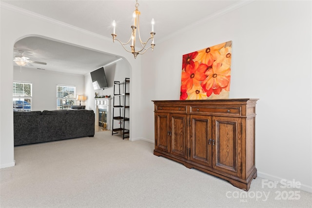 living area featuring baseboards, arched walkways, crown molding, ceiling fan with notable chandelier, and light colored carpet