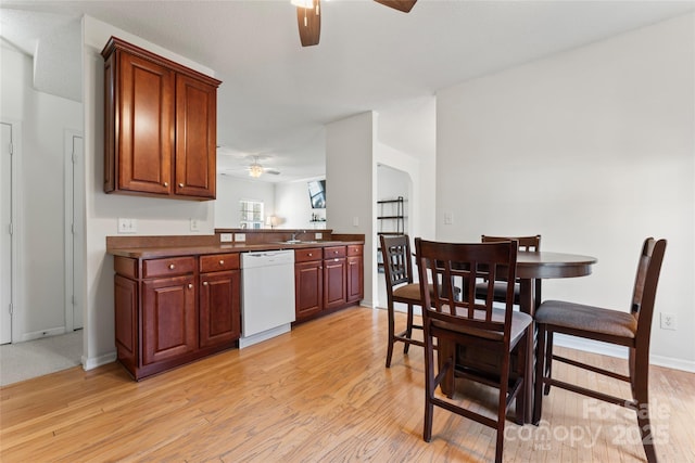 kitchen featuring light wood-style flooring, white dishwasher, ceiling fan, a sink, and dark countertops