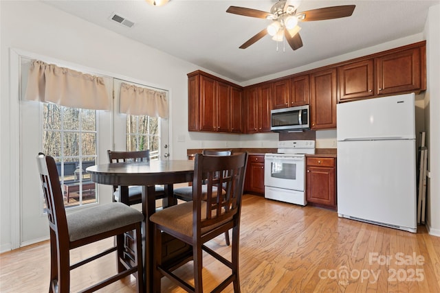 kitchen with white appliances, a ceiling fan, visible vents, and light wood finished floors