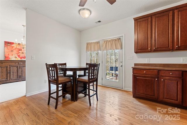 dining room with baseboards, light wood-style floors, visible vents, and ceiling fan