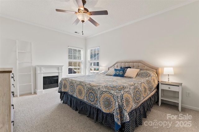 bedroom with visible vents, carpet, a glass covered fireplace, and crown molding