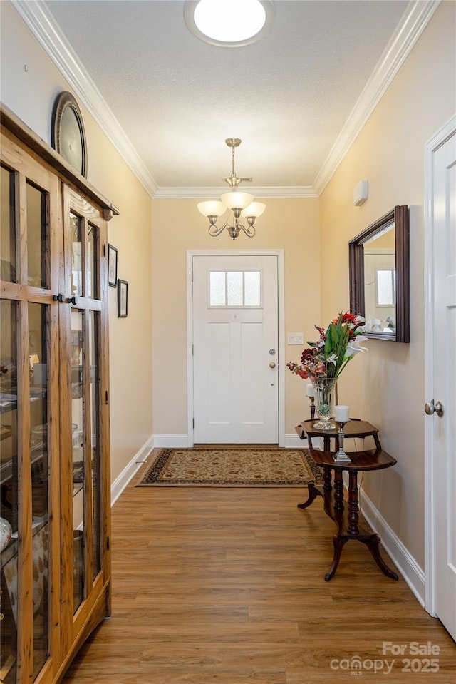 entryway featuring ornamental molding, plenty of natural light, wood finished floors, and a notable chandelier