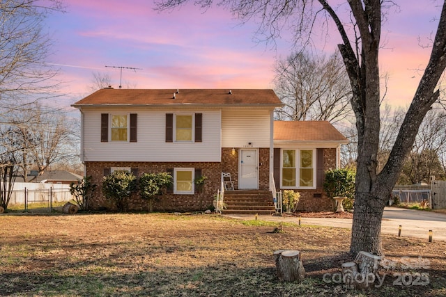 split level home with brick siding and fence