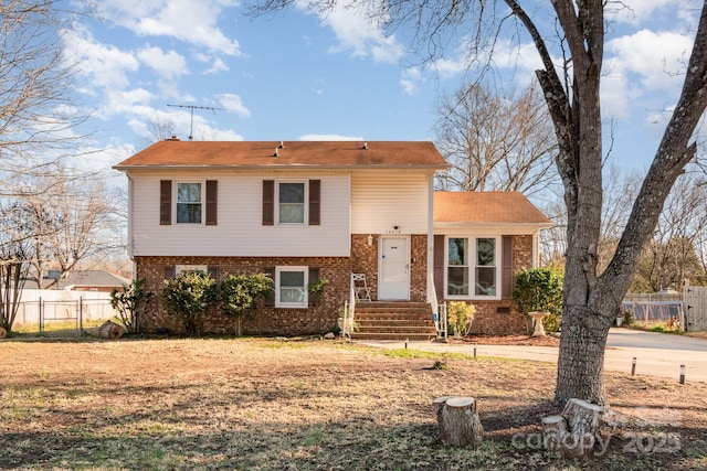 split level home featuring fence and brick siding