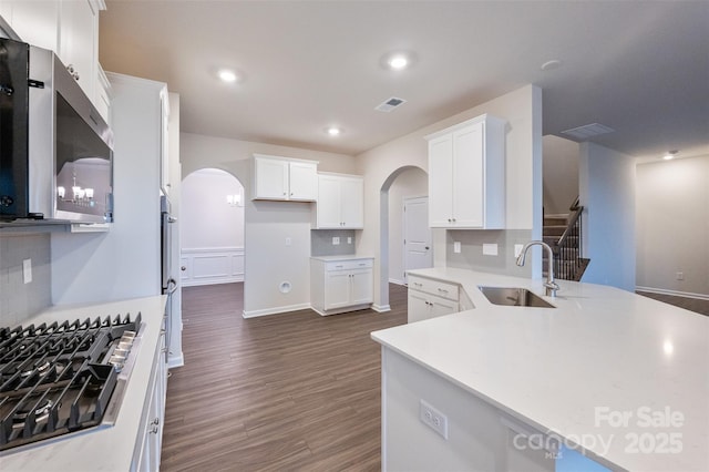 kitchen featuring gas stovetop, light countertops, stainless steel microwave, white cabinets, and a sink