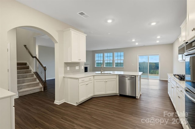 kitchen featuring visible vents, appliances with stainless steel finishes, a peninsula, light countertops, and a sink