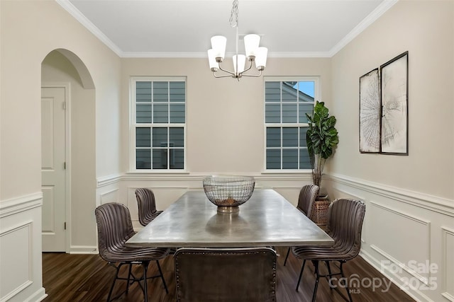 dining space featuring arched walkways, a chandelier, wainscoting, dark wood-style floors, and crown molding