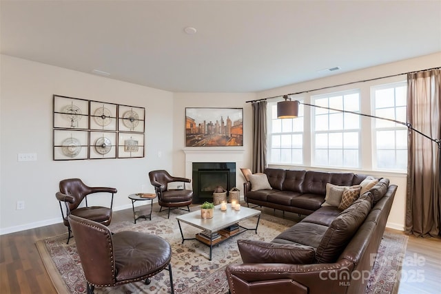 living room with visible vents, wood finished floors, a wealth of natural light, and a glass covered fireplace