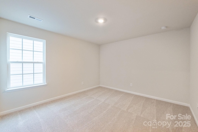 spare room with light colored carpet, visible vents, and baseboards