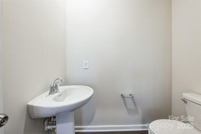 bathroom with a sink, toilet, and baseboards