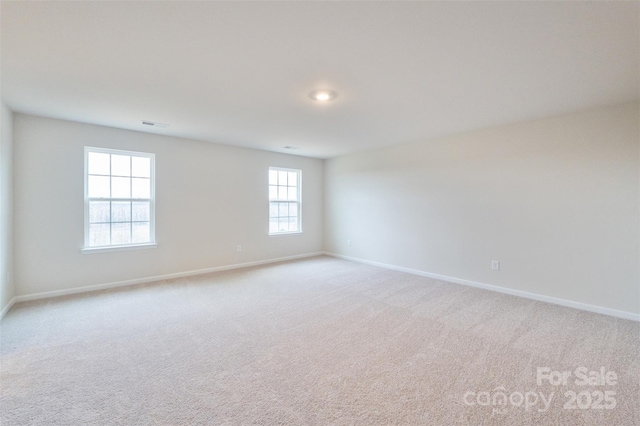 empty room featuring light carpet, visible vents, and baseboards