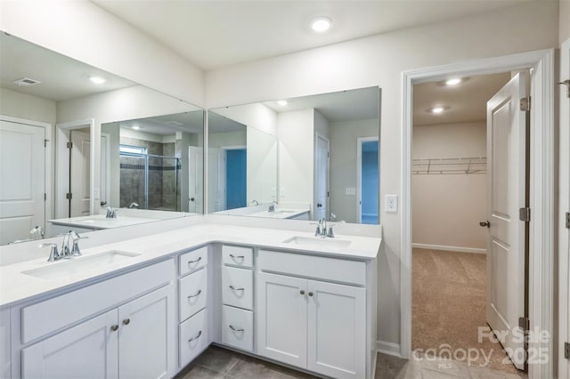 bathroom with a spacious closet, double vanity, a sink, and recessed lighting