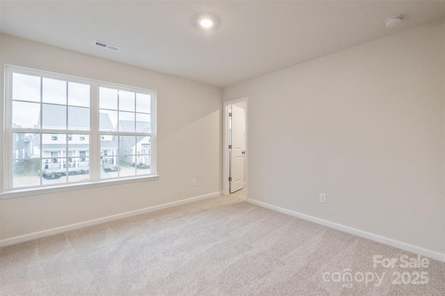 empty room with baseboards, visible vents, and light colored carpet