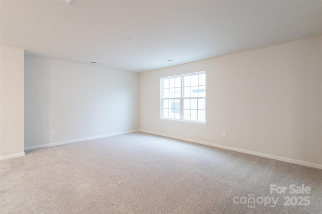 empty room featuring baseboards, visible vents, and light colored carpet