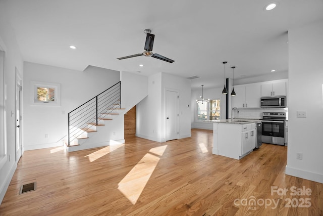 kitchen with stainless steel appliances, a sink, visible vents, light wood-style floors, and open floor plan