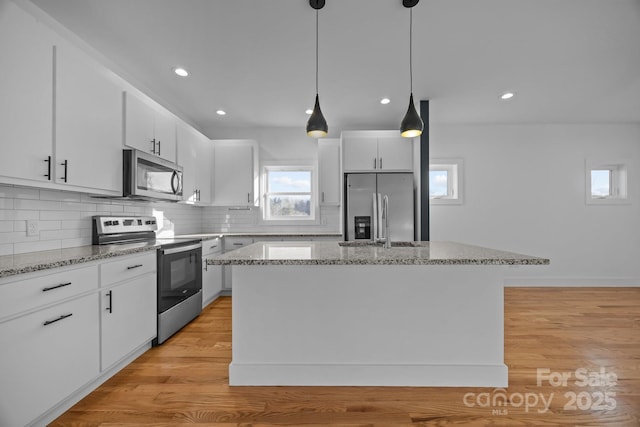 kitchen with white cabinetry, appliances with stainless steel finishes, light wood-type flooring, decorative backsplash, and a center island