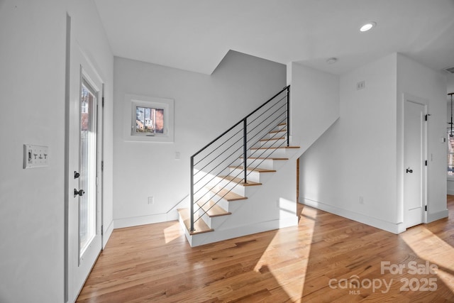 entryway with stairs, wood finished floors, visible vents, and baseboards