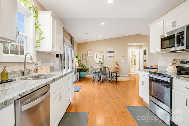 kitchen with lofted ceiling, light wood-style flooring, a sink, white cabinetry, and appliances with stainless steel finishes