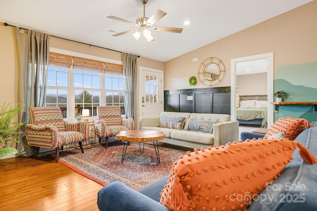 living room with lofted ceiling, visible vents, ceiling fan, and hardwood / wood-style flooring