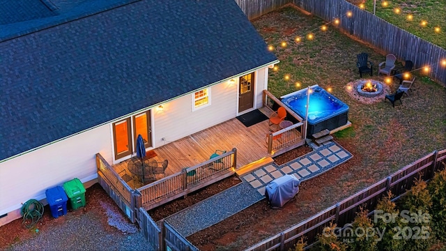 exterior space featuring a deck, a shingled roof, a fenced backyard, and a hot tub