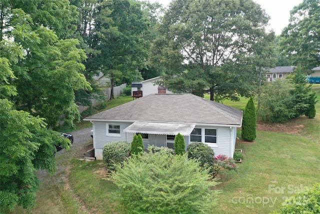 exterior space with roof with shingles and a front yard