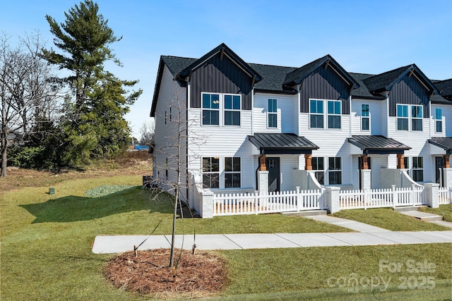 view of front of home featuring a fenced front yard, metal roof, a standing seam roof, a front lawn, and board and batten siding