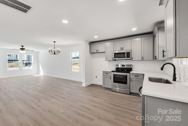 kitchen featuring light countertops, visible vents, gray cabinetry, appliances with stainless steel finishes, and a sink