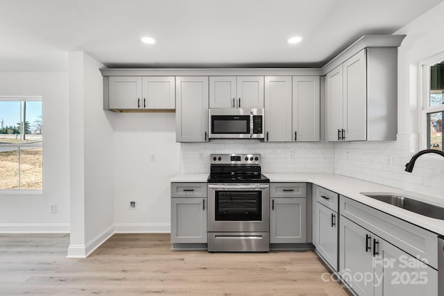 kitchen featuring light countertops, appliances with stainless steel finishes, gray cabinets, and a sink