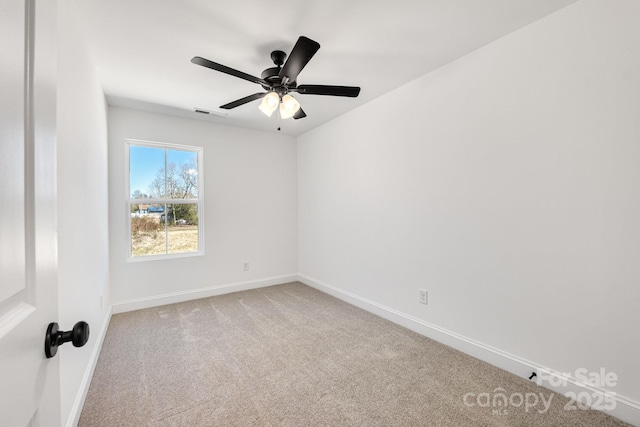 carpeted spare room featuring a ceiling fan and baseboards