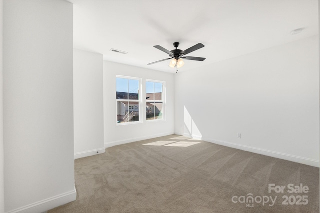 spare room with light carpet, a ceiling fan, visible vents, and baseboards