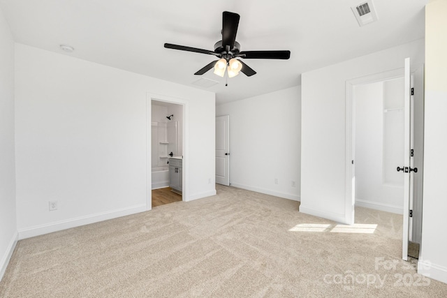 unfurnished bedroom featuring light carpet, a spacious closet, baseboards, and a closet