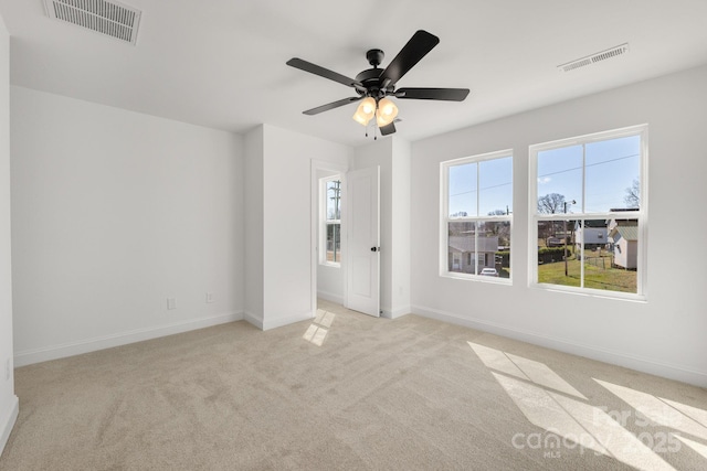 unfurnished bedroom featuring baseboards, ceiling fan, visible vents, and light colored carpet