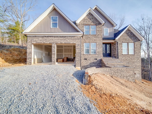 craftsman-style house featuring gravel driveway, brick siding, board and batten siding, crawl space, and a garage