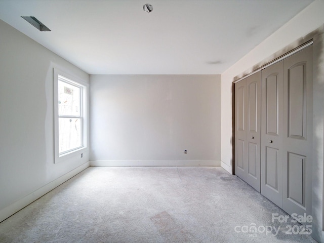 unfurnished bedroom featuring a closet, light colored carpet, and baseboards