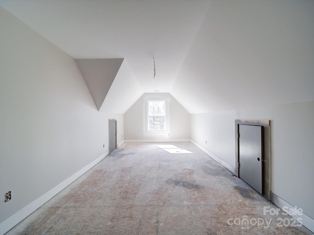 bonus room with lofted ceiling, light carpet, and baseboards