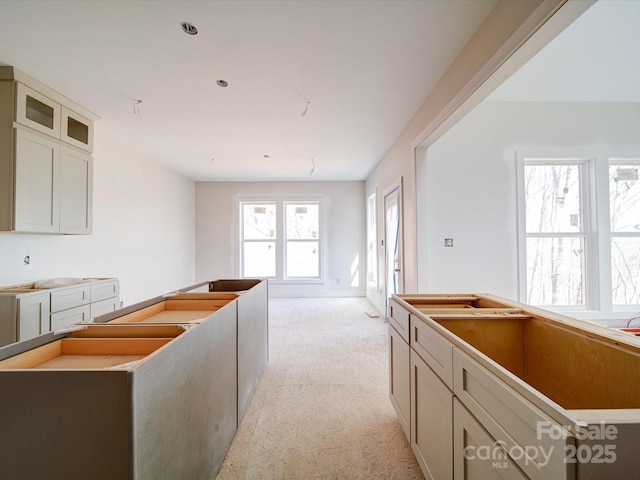 kitchen featuring glass insert cabinets, a center island, light colored carpet, and cream cabinets