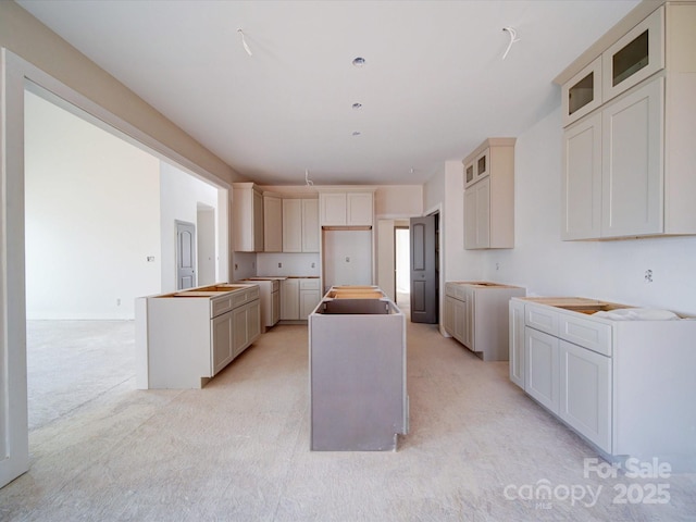 kitchen with light carpet, glass insert cabinets, and a center island