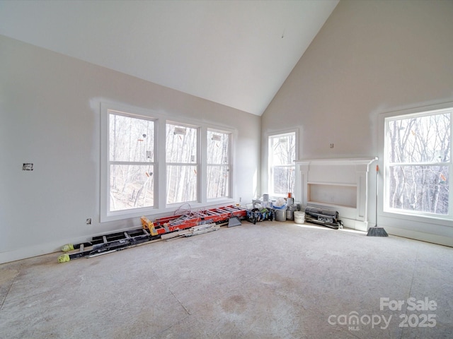 unfurnished living room with high vaulted ceiling and carpet flooring