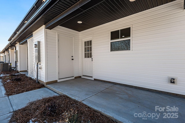 view of exterior entry with a patio and central AC unit