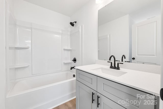 full bath with tub / shower combination, wood finished floors, and vanity