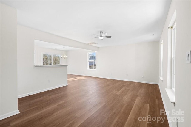 spare room featuring dark wood-style floors, ceiling fan with notable chandelier, visible vents, and baseboards