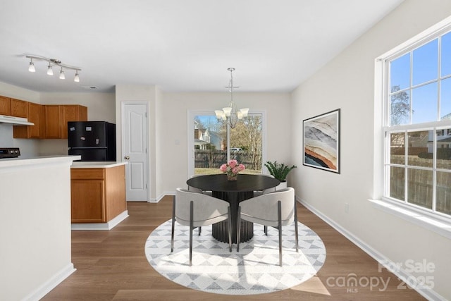 dining room featuring dark wood-style flooring, baseboards, and an inviting chandelier