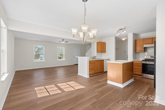 kitchen featuring decorative light fixtures, light countertops, electric range, open floor plan, and a kitchen island